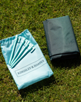 Light blue drawstring bag with five teal tent stakes and gray cover in Socialite Picnic Set