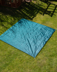 Teal quilted tarp from The Socialite Picnic Set on grass