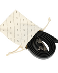 Black leather belt with a silver-toned automatic buckle, presented in a cream-colored drawstring pouch.