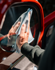 Light blue microfiber cloth wiping car side mirror in The Detailer Car Cleaning Set