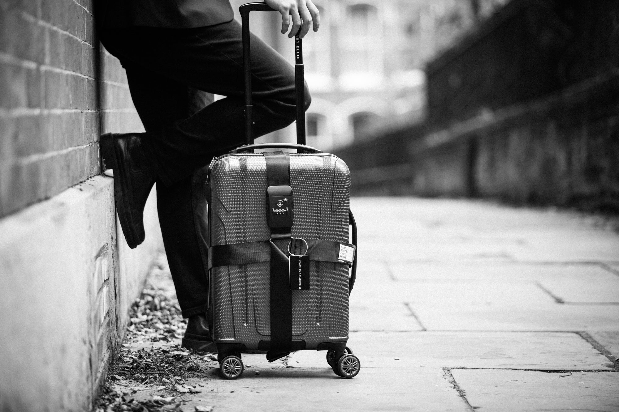 A sleek, textured hard-shell suitcase with a black retractable handle and reinforced straps.