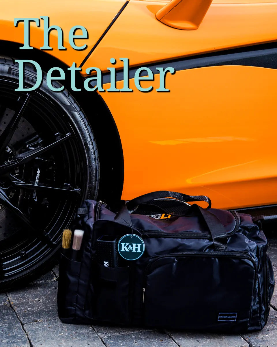 Black duffel bag with K&H logo next to an orange car